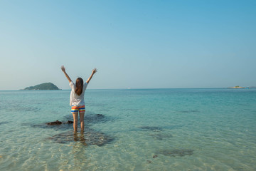 Happy woman standing arms outstretched on the beach at Sea