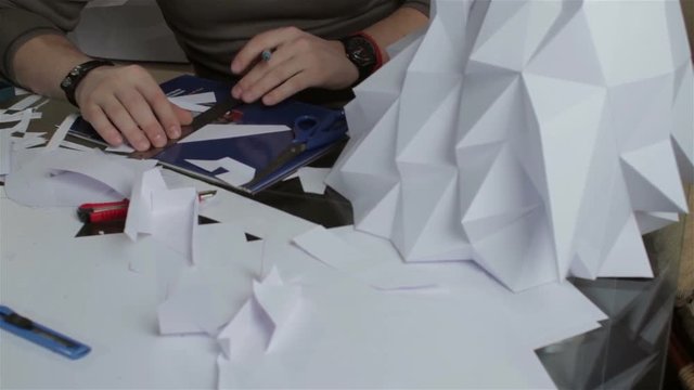 Man makes paper wolf's head.