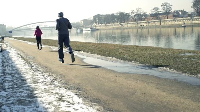 People jogging in city on pavement near river, super slow motion 240fps
