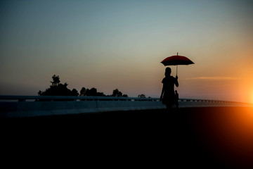Fototapeta na wymiar Silhouette women umbrella looking horizon.