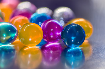 Blue, yellow and purple orb with reflection, against a background of colorful balloons, abstract background