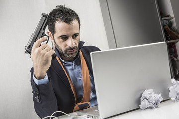 uomo con la pistola guarda arrabbiato il suo computer con aria minacciosa