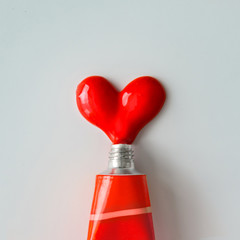 Red paint in shape of a heart on white paper background. Flat lay. Love concept.
