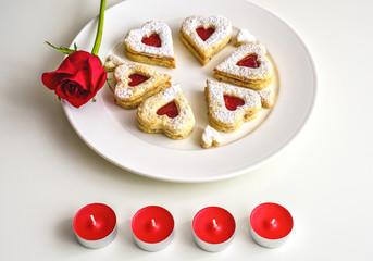 Homemade Heart shaped Almond Linzer cookies on white plate. Romantic set up red roses and candle lights ffor anniversary, wedding, Valentine Day
