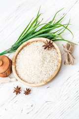 rice in wooden plate and anise on white wooden background. Rice and spices in ecological container. Set for cooking. Set for spa.