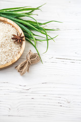 rice in wooden plate and anise on white wooden background. Rice and spices in ecological container. Set for cooking. Set for spa.