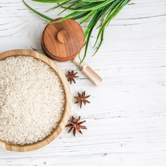 rice in wooden plate and anise on white wooden background. Rice and spices in ecological container. Set for cooking. Set for spa.