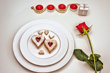 Homemade Heart shaped Almond Linzer cookies on white plate. Romantic set up red roses and candle lights ffor anniversary, wedding, Valentine Day