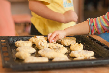 Little girl puts hand made biscuits on baking tray in Waldorf kindergarten