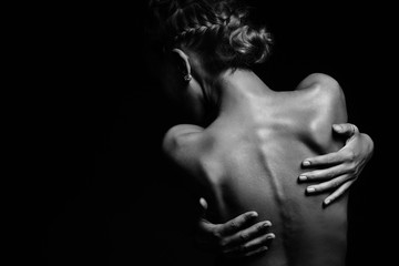 Black and white picture of a naked girl who hugs herself