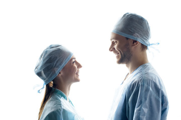 side view of smiling surgeons in medical uniform looking at each other on white