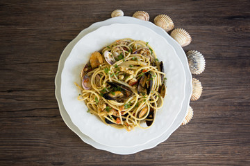 Spaghetti with seafood in white ceramic plate on wooden background