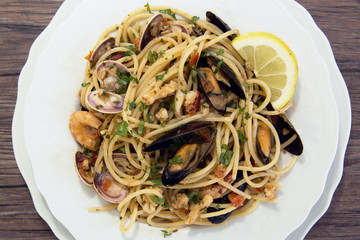 Spaghetti with seafood in white ceramic plate on wooden background