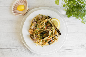 Spaghetti with seafood in white ceramic plate on wooden background