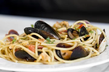 Photo sur Plexiglas Crustacés Spaghetti aux fruits de mer dans une assiette en céramique blanche sur fond de bois