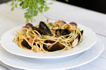 Spaghetti with seafood in white ceramic plate on wooden background