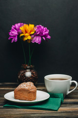 violet and yellow flowers in a vase, a cup with a drink and a floury product
