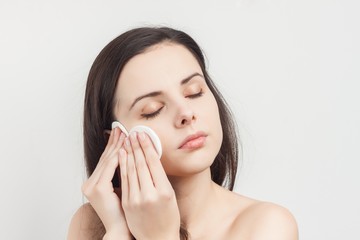 woman wiping her face with cotton pads