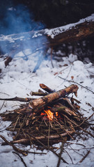 Fire burns in the snow in the woods, on a background of snow