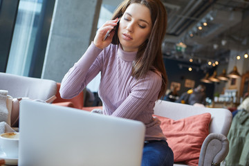 Image of young female reading sms on the phone in cafe
