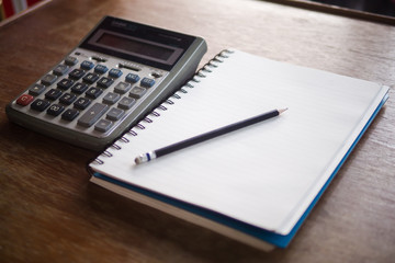 Blank notebook pencil and calculator on wood table