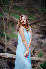 outdoor portrait of a beautiful brunette model in blue dress in the spring forest