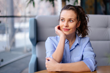 Pretty girl sitting on the bench in cafe place and looking forward