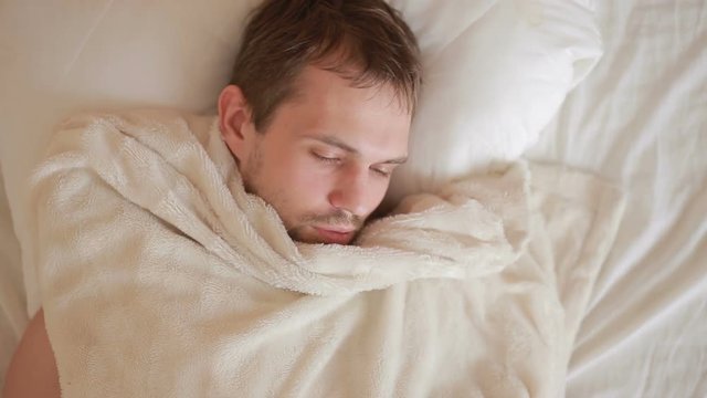 a man with a fever is lying in bed at home