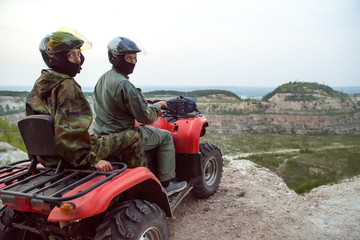 Beautiful couple is watching the sunset from the mountain sitting on a quadbike. © diter