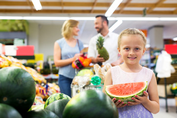 Girl holding slice of watermelon in shop