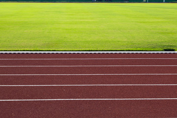 red running track and green grass in stadium