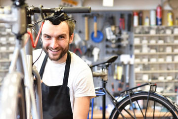 Fototapeta na wymiar sympathischer Fahrradmechaniker in der Werkstatt repariert ein Fahrrad // mechanic repairs a bicycle