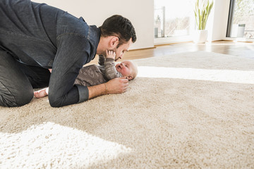 Father and baby son playing on carpet at home