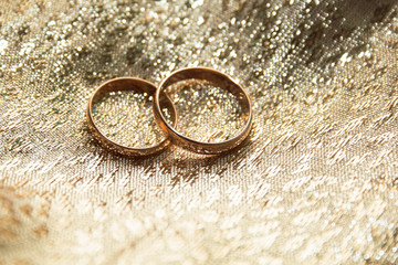 Obraz na płótnie Canvas gold wedding rings on a gold cloth background