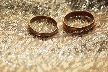 Obraz na płótnie Canvas gold wedding rings on a gold cloth background