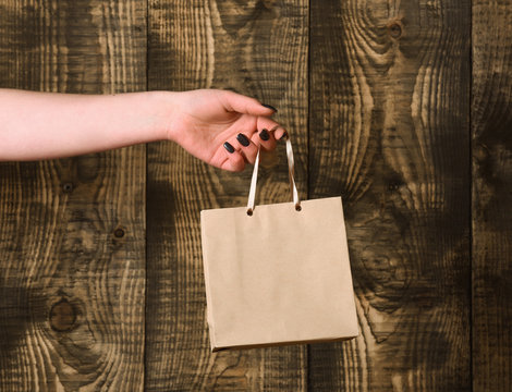 brown grey shopping bag in female hand on wooden background