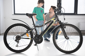 Fototapeta na wymiar Full length view of new bicycle and happy father with son looking at each other