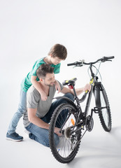 Fototapeta na wymiar Happy father and son hugging while inspecting new bicycle on white