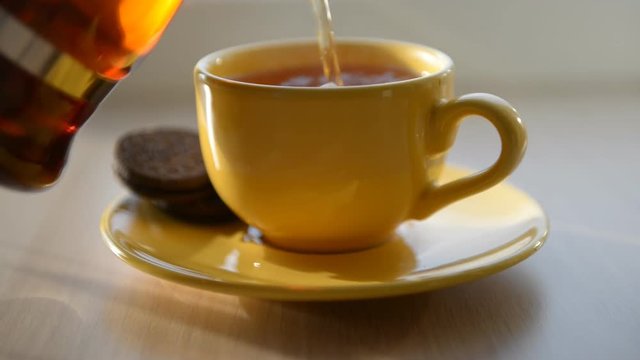 Tea being poured into yellow cup
