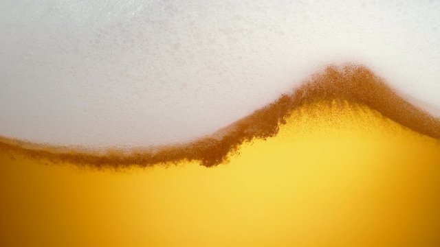 Extreme close-up beer in glass. Foam moving. Shot with high speed camera, phantom flex 4K. Slow Motion.