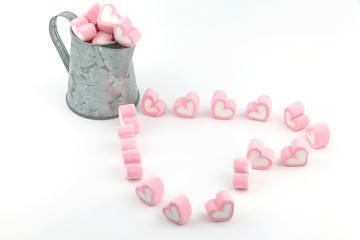 Heart of pink marshmallows in pitcher on white background
