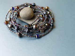 Beads of pearl and black glass and gray sea stones on a blue background.