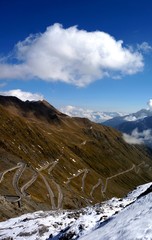 Kehren auf Pass Straße mit tiefblauem Himmel und großer Wolke / Stilfser Joch / Südtirol