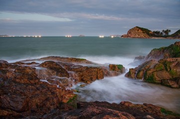 A rocky ocean coastline slow exposure with large rocks covered in moss in Vung Lam Bay Vietnam.