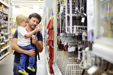 Father and his son choosing the right tool in a hardware store - obrazy, fototapety, plakaty