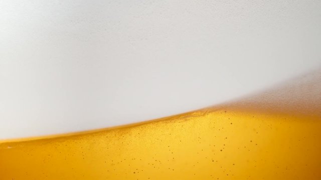 Extreme close-up beer in glass. Foam moving. Shot with high speed camera, phantom flex 4K. Slow Motion.