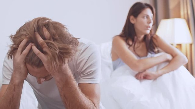 Two young Caucasian beautiful lovers ajar with each other sitting in bed in the morning arguing in slowmotion