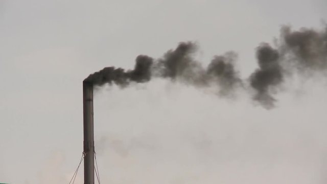 Black smoke from factory chimney pollutes the atmosphere and environment