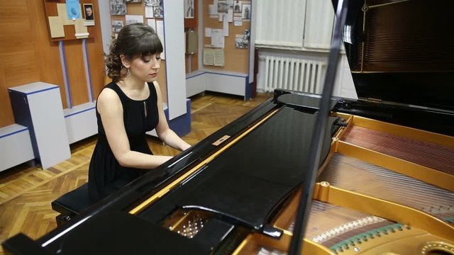 Happy talented young lady playing grand piano. Pianist musician plays piano, fingers touching piano keyboard. Fingers typing on piano keys. Camera slowly moving