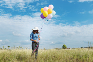 asia woman at meadow with balloons in hand.